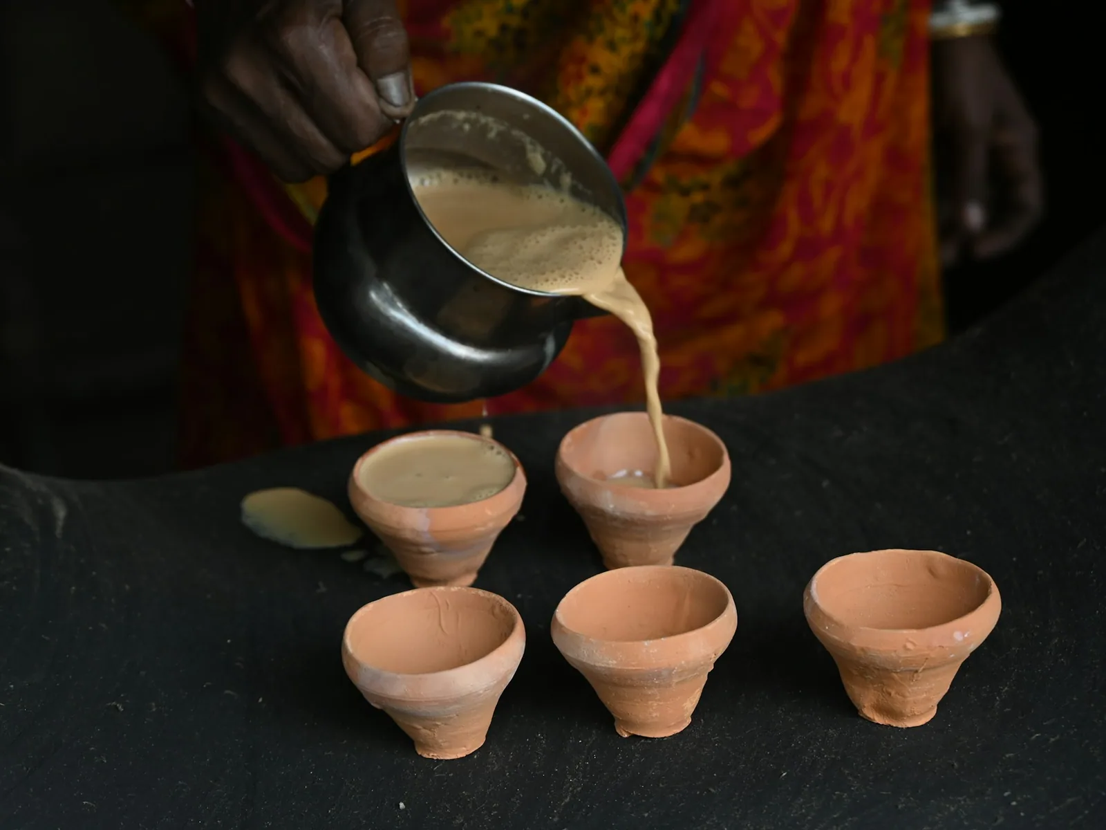 Du chai est versé dans de petites tasses en terre cuite, symbole d’un accueil chaleureux.